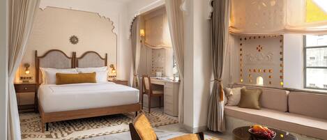 Une chambre d’hôtel comprenant un lit, un bureau, une chaise, un canapé, un ventilateur de plafond et une fenêtre avec des rideaux.