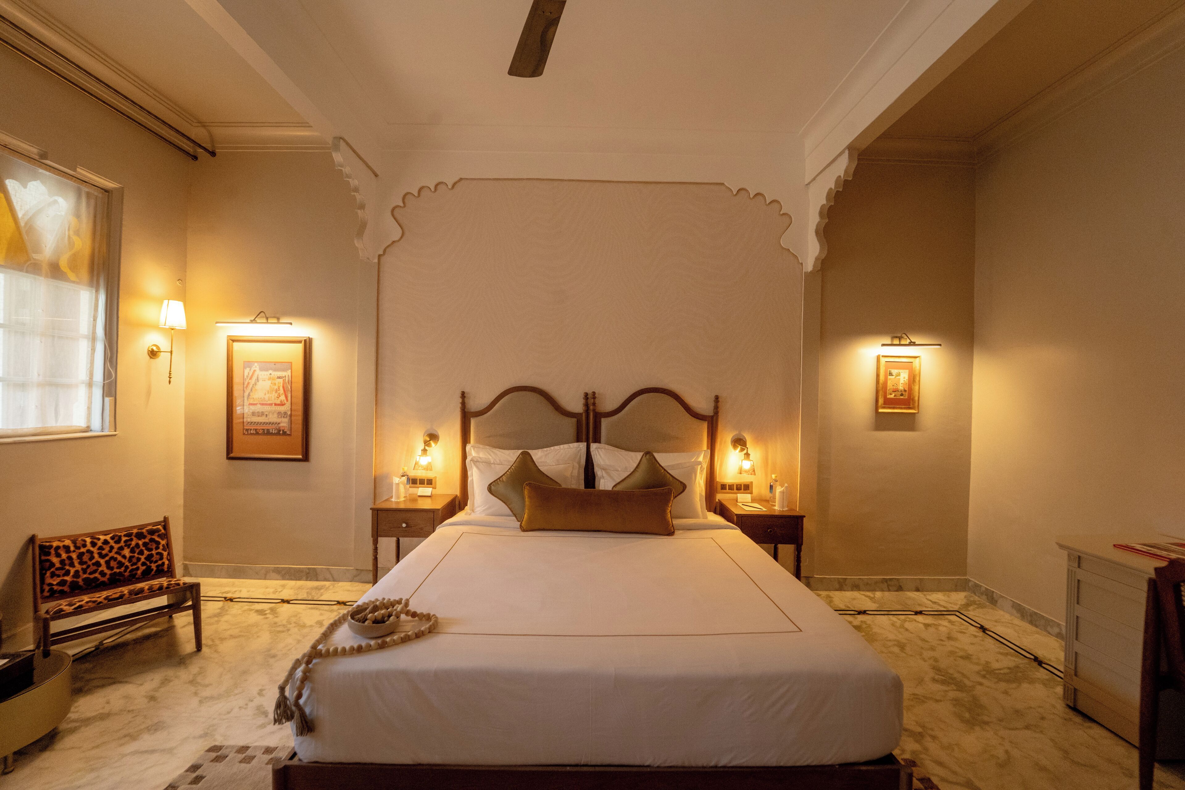 Habitació d'hotel amb un llit gran, dues taules de nit amb làmpades, una panxa i un quadre al mur.