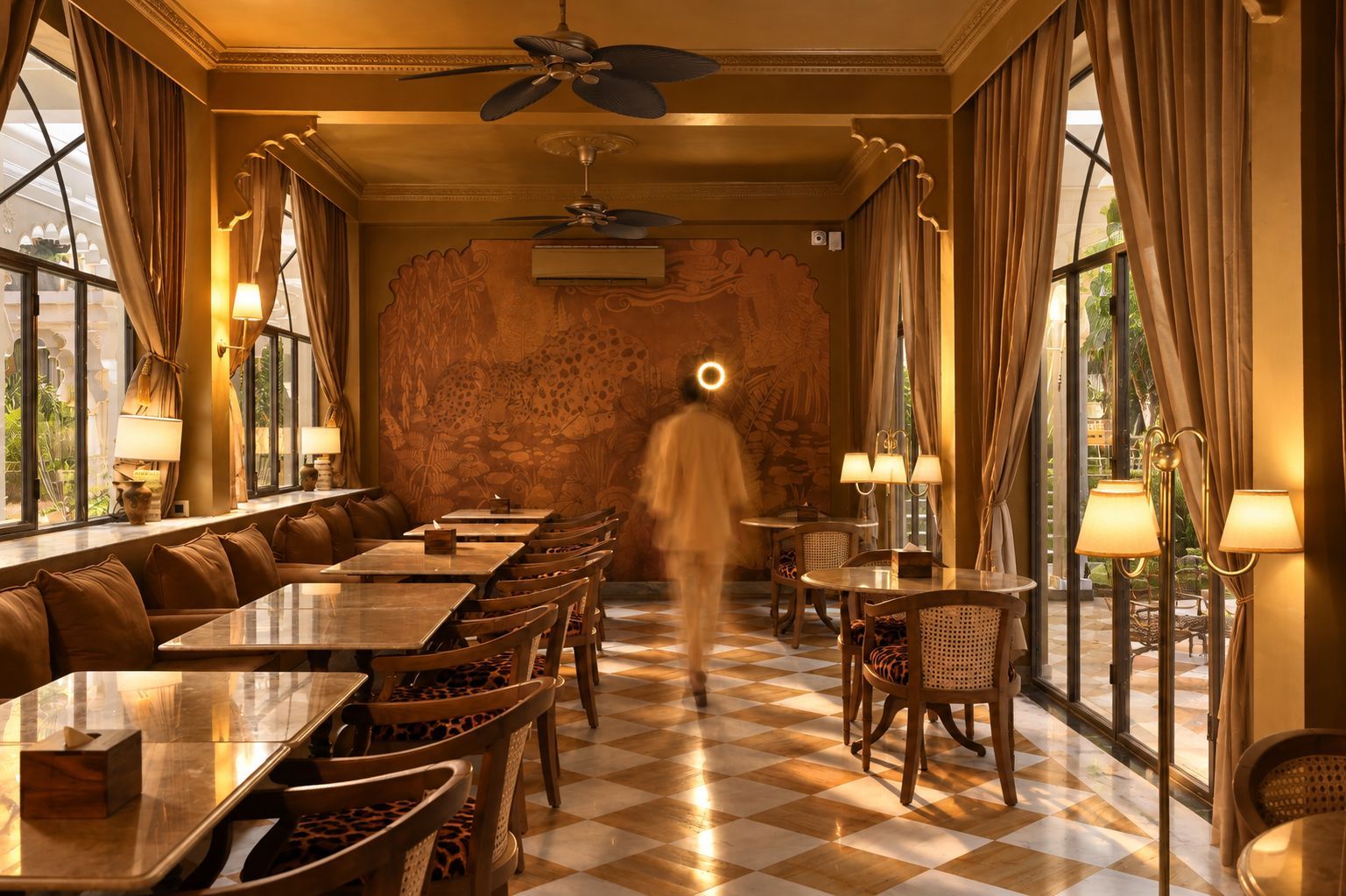 Un restaurant avec un sol à carreaux, de longues tables et des chaises, un grand mur en pierre et des fenêtres avec des rideaux.