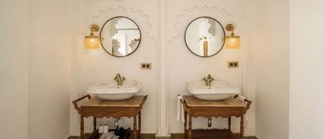 A bathroom with two sinks, each with a mirror and wall-mounted light fixture.