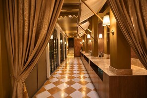 A hotel corridor with checkered flooring, multiple sinks, and warm lighting. - Mewar Manor by My Downtown Hotels - Jhadol Haveli (Udaipur)