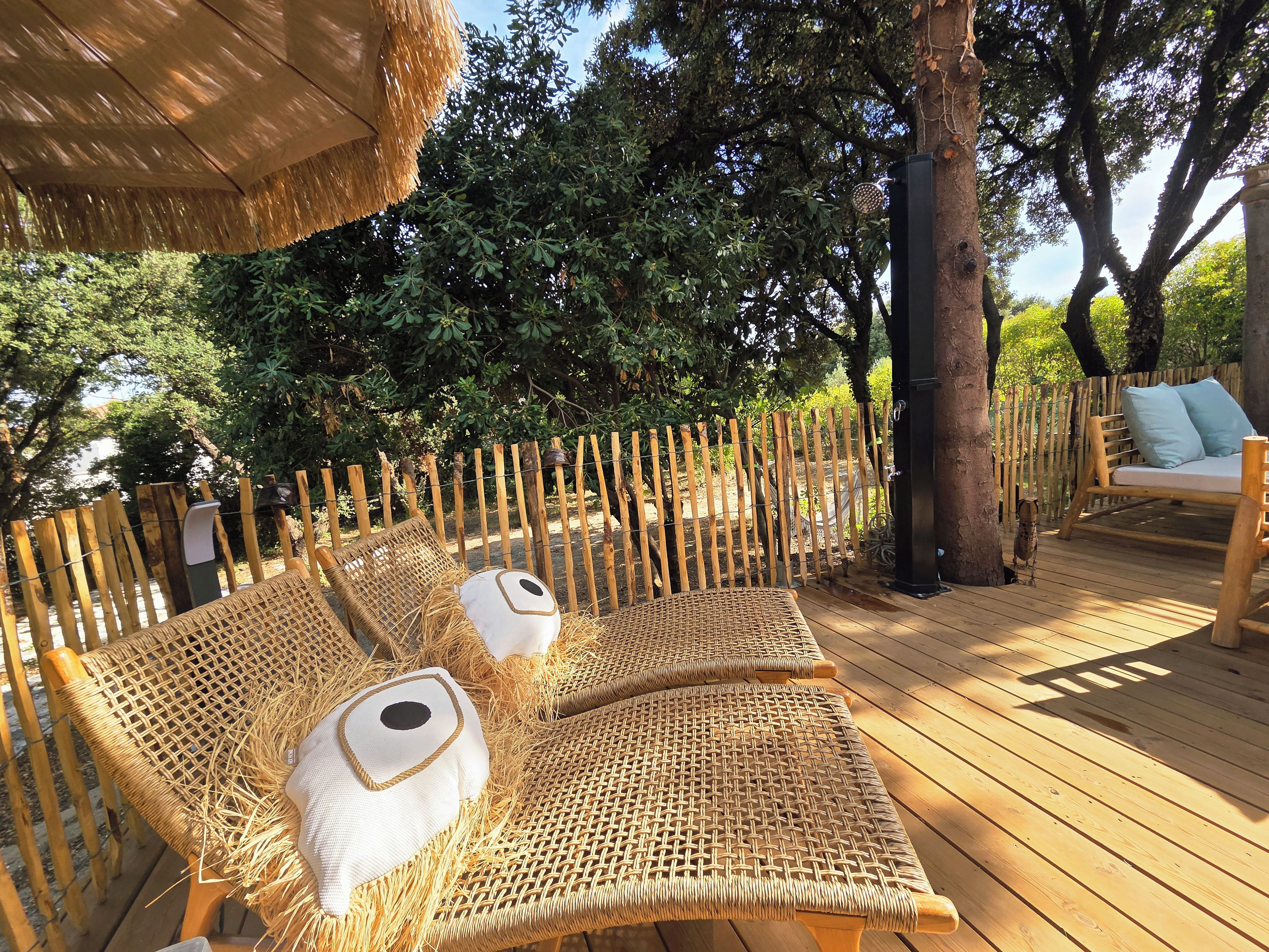 A wooden deck with wicker furniture and a thatched roof.