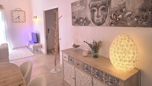 A modern living room with a large Buddha painting, a decorative light, and a minimalist design. - Les Yeux Bleus: Bohemian Cottage, Petanque, and Spa, 25 Minutes from the Sea (Restinclières)