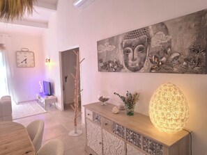 Ein modernes Wohnzimmer mit einem großen Buddha-Gemälde, einer Zierleuchte und einem minimalistischen Design.