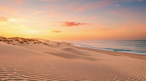A beach with sand dunes and ocean waves.