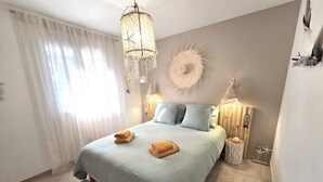 A bedroom with a bed, two bedside lamps, a wall clock, and a decorative wall piece. - Les Yeux Bleus: Bohemian Cottage, Petanque, and Spa, 25 Minutes from the Sea (Restinclières)