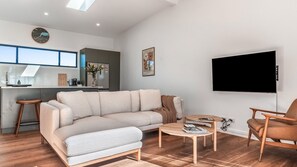 Ein modernes Wohnzimmer mit einer Couch, einem Couchtisch und einem Fernseher.