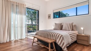 Una camera da letto con un letto, comodini, una panca, una finestra e vista sull'esterno.