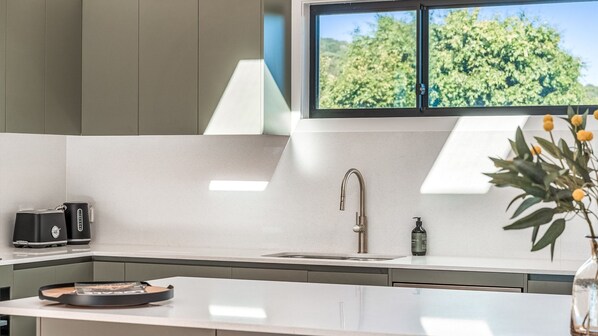 A modern kitchen with a built-in oven, a sink, and a window overlooking greenery. - Fernleigh Stay - A Northern Rivers Hinterland Retreat (Fernleigh)