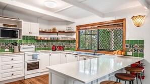 Cocina moderna con armarios blancos, una isla grande, microondas y ventana con vistas.