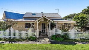 A two-story house with a front porch, white picket fence, and a number '18' on the fence.