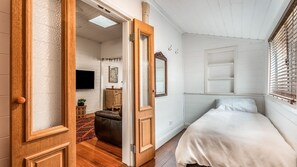 Ein Schlafzimmer mit einem Bett, einem Schminktisch, einem Fernseher und einer Tür zu einem anderen Raum.