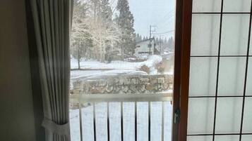Une pièce avec vue sur un paysage enneigé, accessible par une porte coulissante.