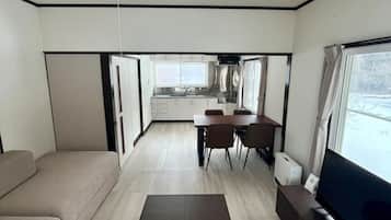 Un salon moderne avec un canapé, une table basse, un téléviseur et une cuisine en arrière-plan.