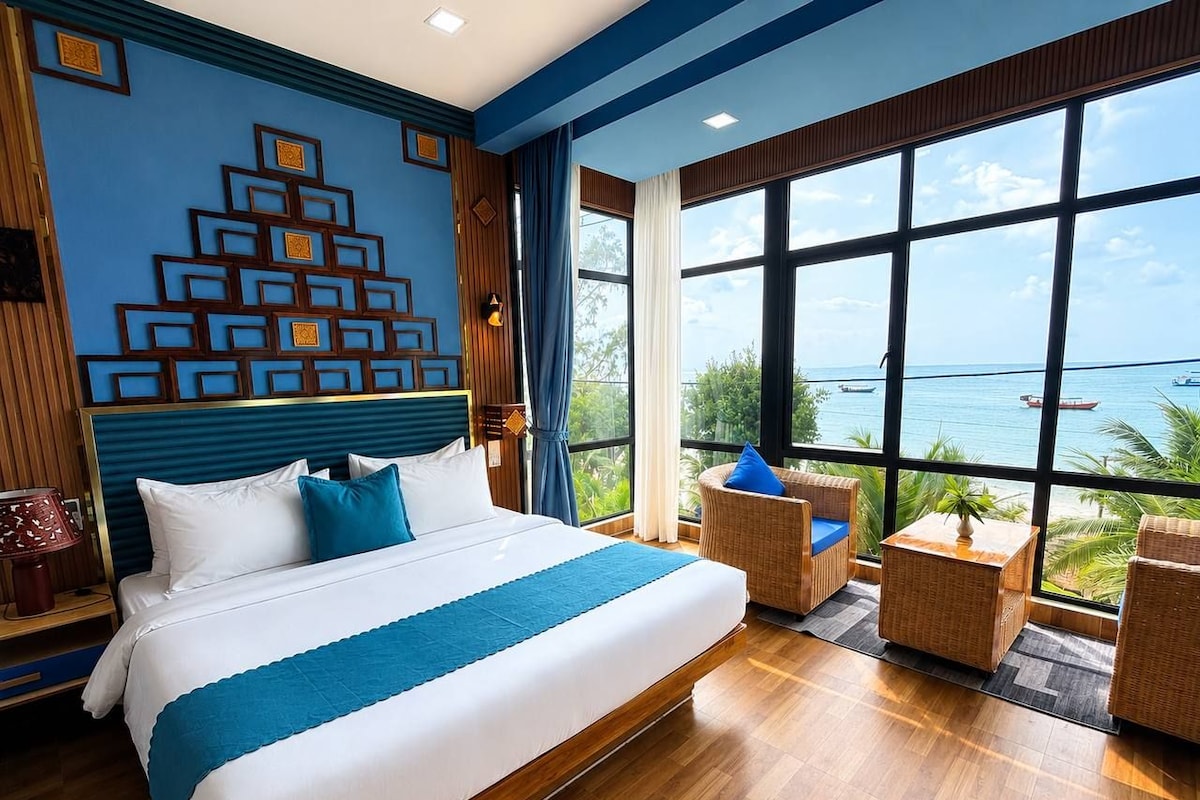 Habitación de hotel con una cama grande, vista al mar y una pared decorativa.