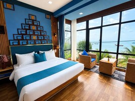 Habitación de hotel con una cama grande, vista al mar y una pared decorativa.