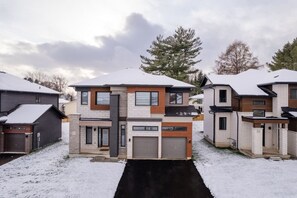 En modern flervåningsbyggnad med bostäder och ett garage, omgiven av snötäckt mark.