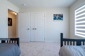 A bedroom with a double door, a bed, a chair, a window with blinds, and a poster on the wall. - Spacious Modern Orillia Family Retreat- Hot Tub (Severn)