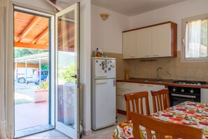 A kitchen with a refrigerator, stove, sink, and a dining table with chairs. - AZIENDA AGRICOLA - APPARTAMENTO 2 (Capoliveri)