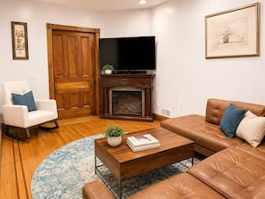 Ein Wohnzimmer mit Kamin, Fernseher, Sofa und Couchtisch.