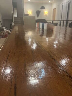 Ein glänzender Holzboden mit spiegelnder Oberfläche, der zu einer Treppe und einem Zimmer mit einem Bett und Wandleuchten führt.