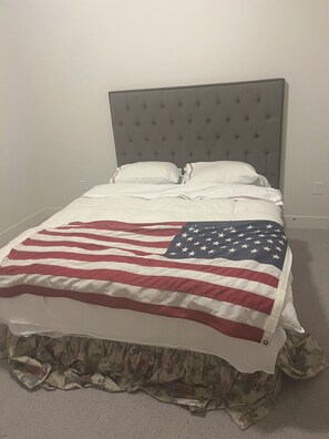 Ein Bett mit Kopfteil, einer Decke mit amerikanischer Flagge und einem blumigen Bettruchkant.