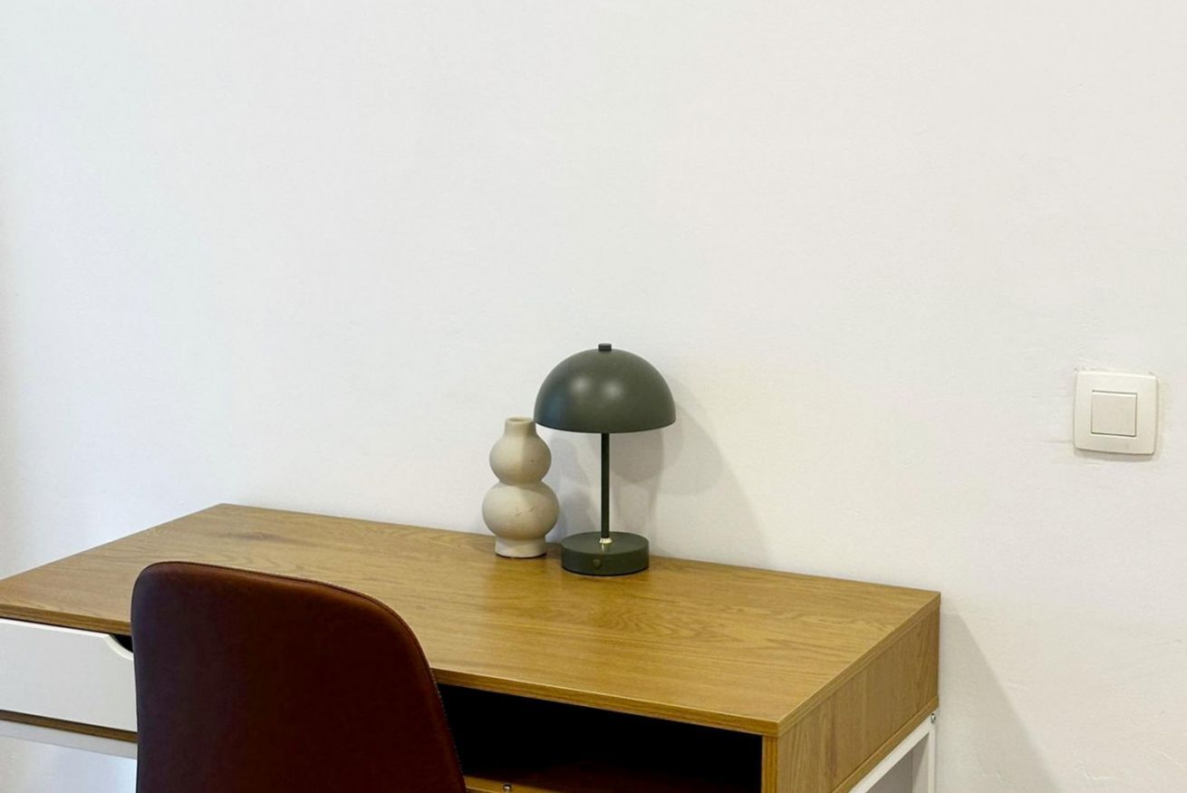Un bureau en bois avec une lampe et deux vases.
