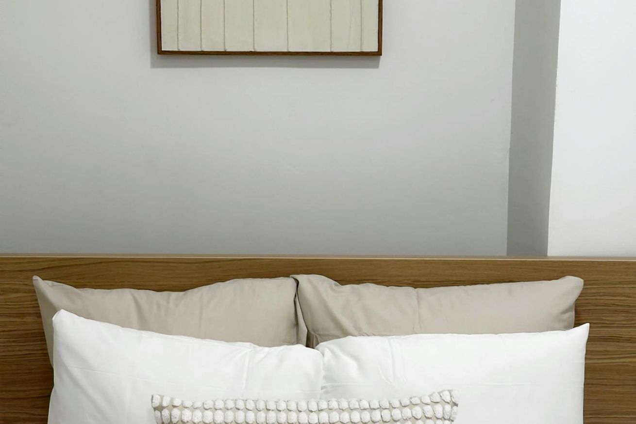 Un lit avec une tête de lit en bois, deux oreillers et un tableau encadré accroché au mur.