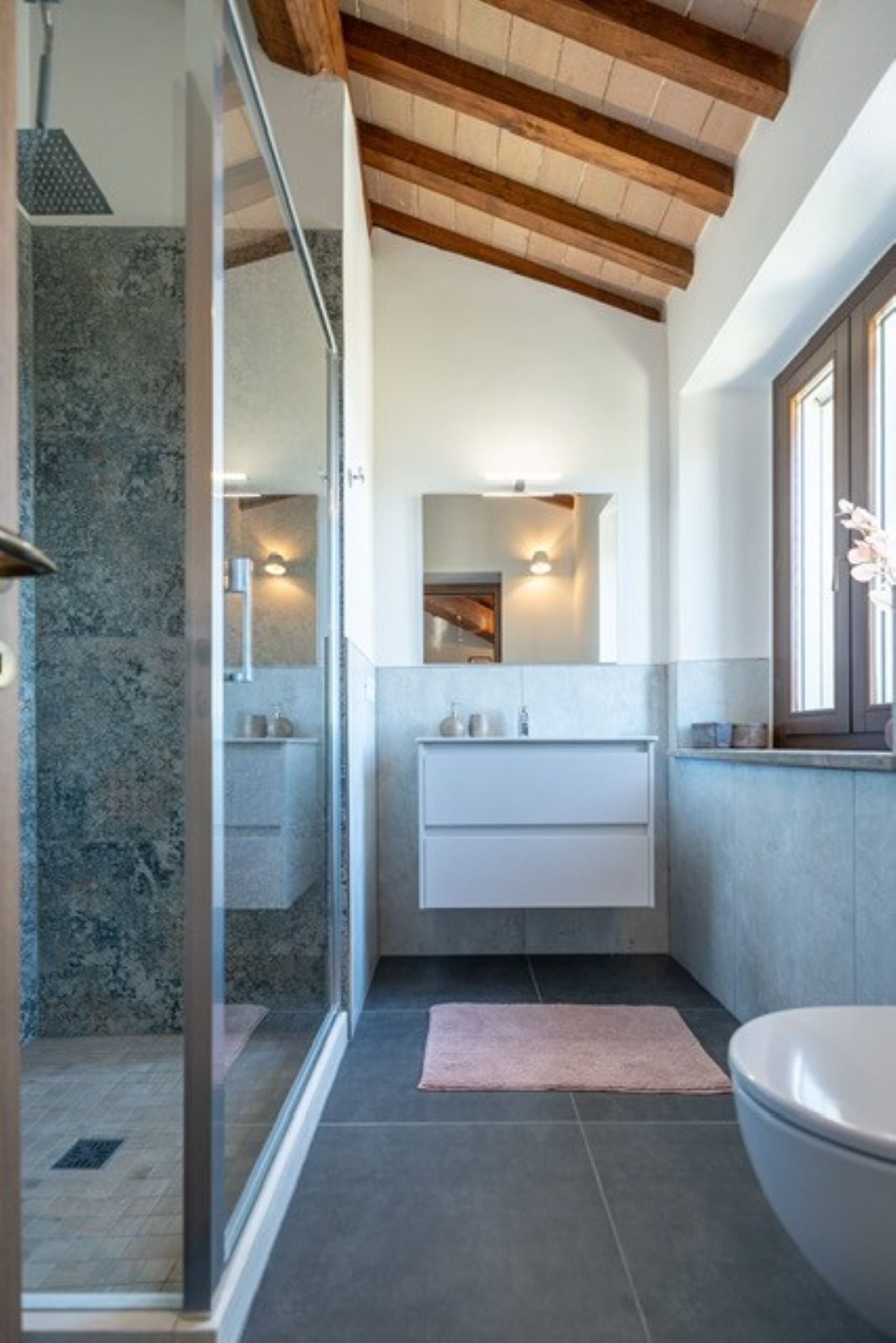 Ein modernes Badezimmer mit Duschkabine aus Glas, einem weißen Waschbecken und einem großen Spiegel.