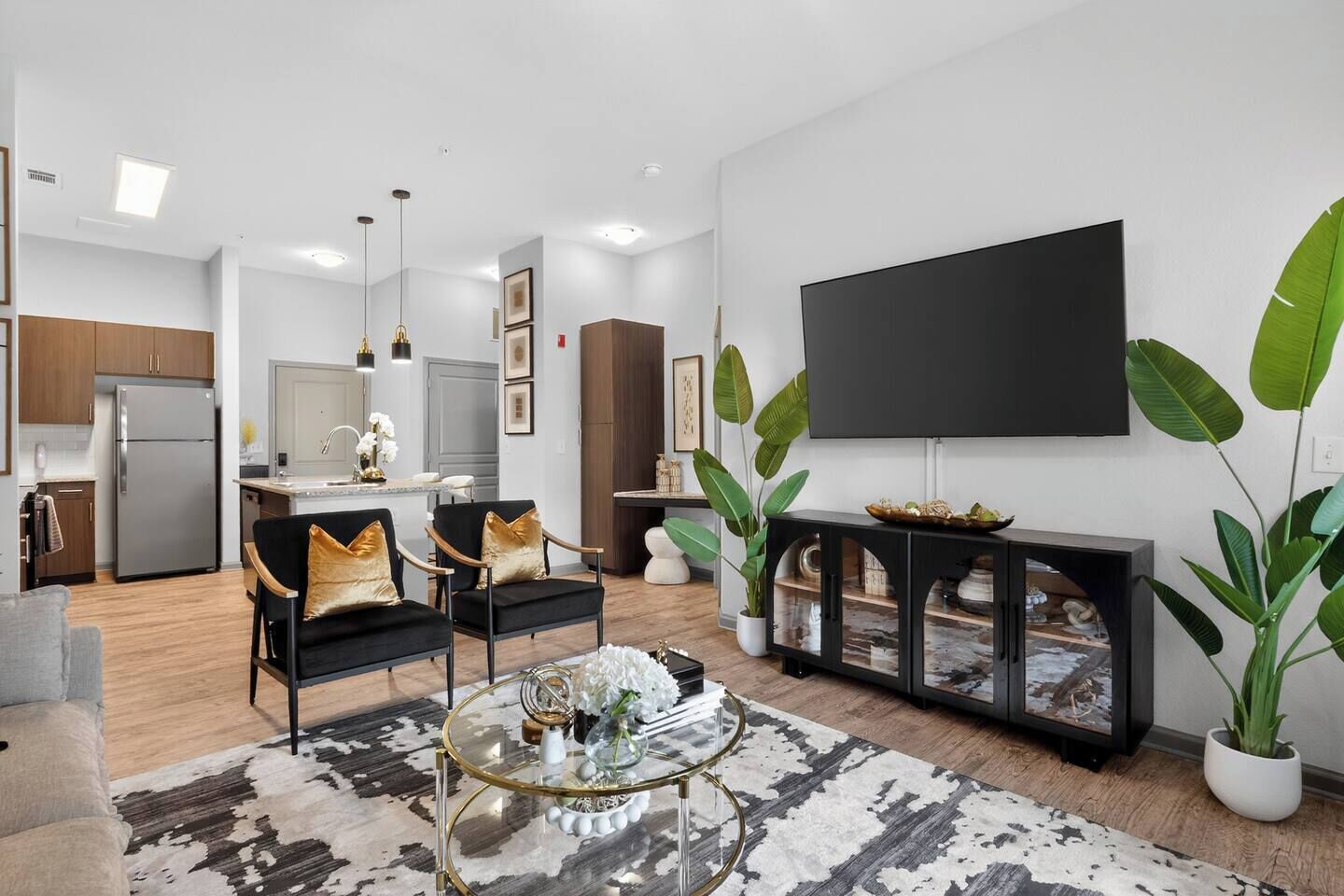 Uma sala de estar moderna com televisão de tela plana, uma mesa de centro e uma área de refeições ao fundo.