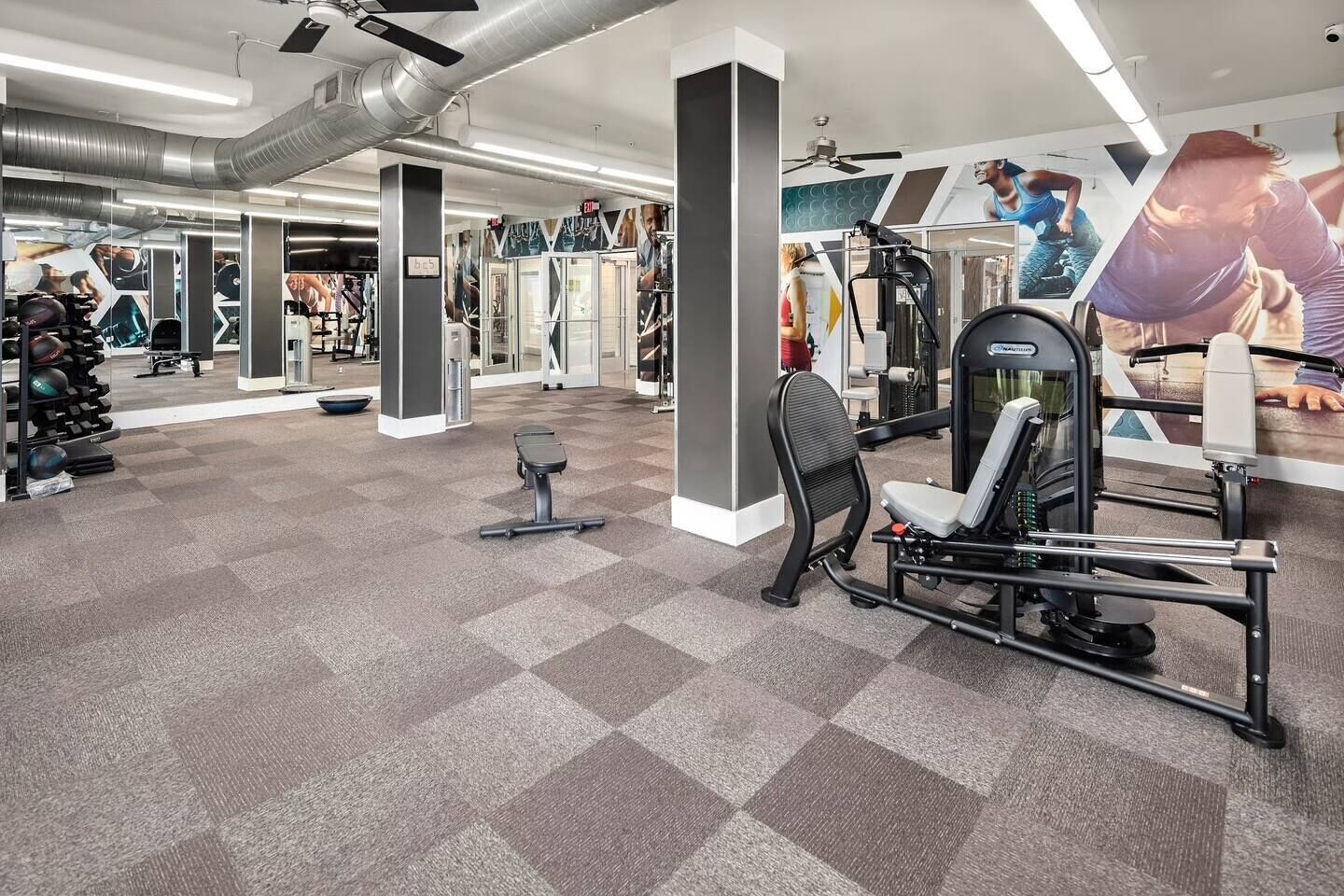 A gym with exercise equipment, mirrors, and a checkered floor.