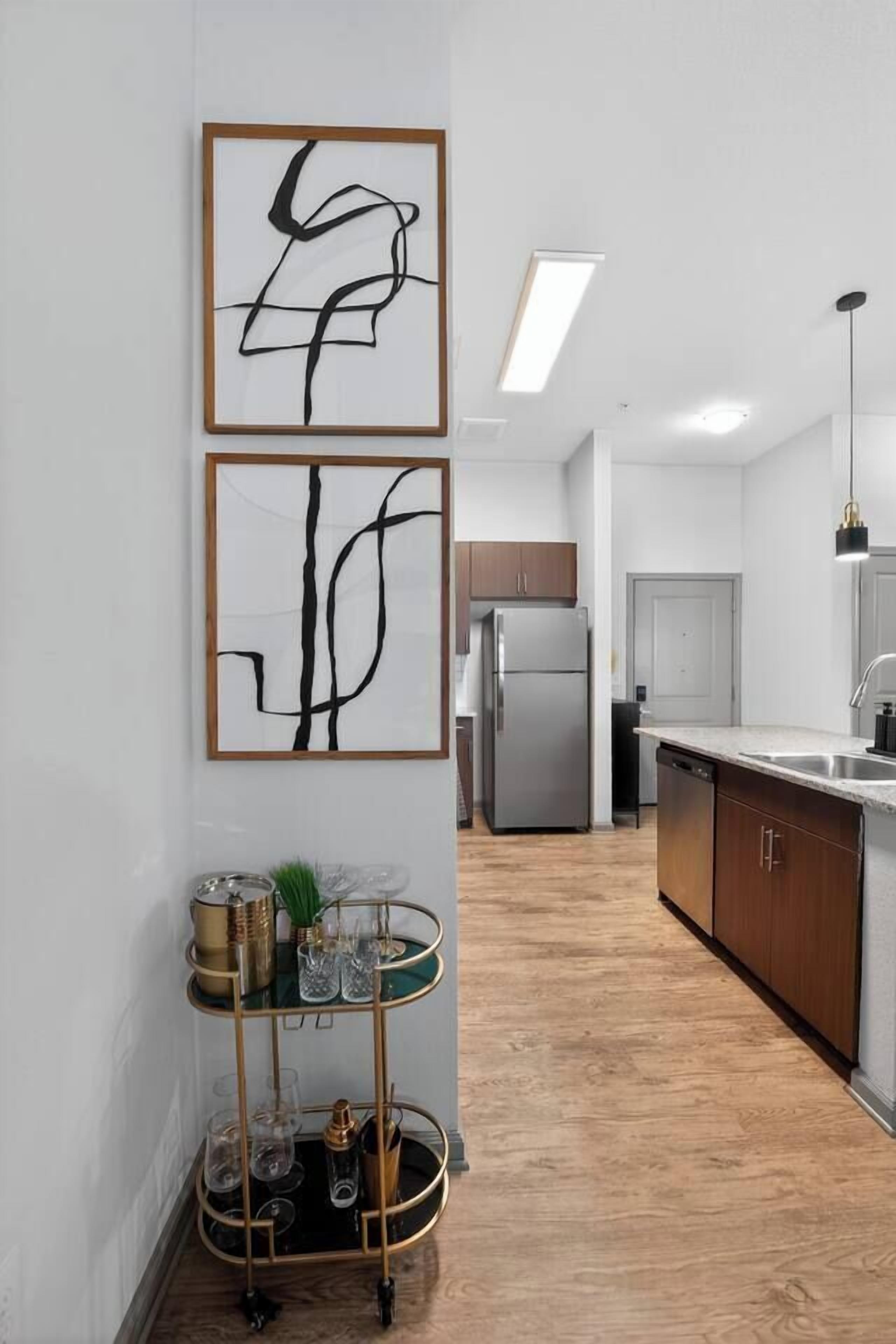 A modern kitchen with a stainless steel refrigerator, wooden cabinets, and a glass coffee table with decorative items.