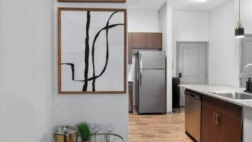 A modern kitchen with a stainless steel refrigerator, wooden cabinets, and a glass coffee table with decorative items.