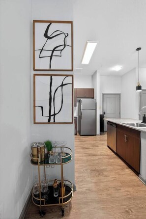 Eine moderne Küche mit einem Edelstahl-Kühlschrank, Holzschränken und einem Glastisch mit Dekoration.