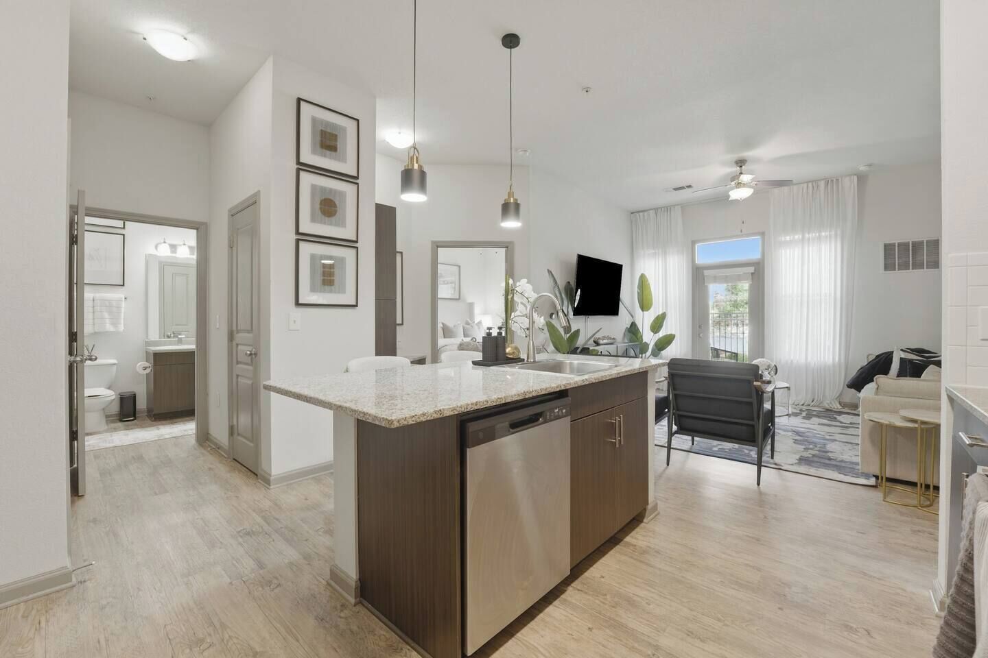 A modern kitchen with a central island, pendant lighting, and a view to the living area.