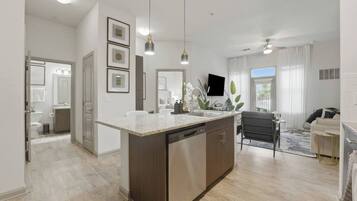 A modern kitchen with a central island, pendant lighting, and a view to the living area.
