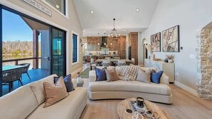 A spacious living area with a large sofa, a coffee table, and a view of the lake. - Pura Vida | Lakefront, Hot Tub, Dock + Game Room (Louisa)
