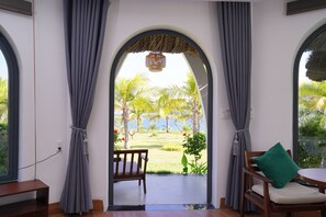 Une porte en arc donnant sur un balcon d’où l’on peut admirer des palmiers et une pelouse.