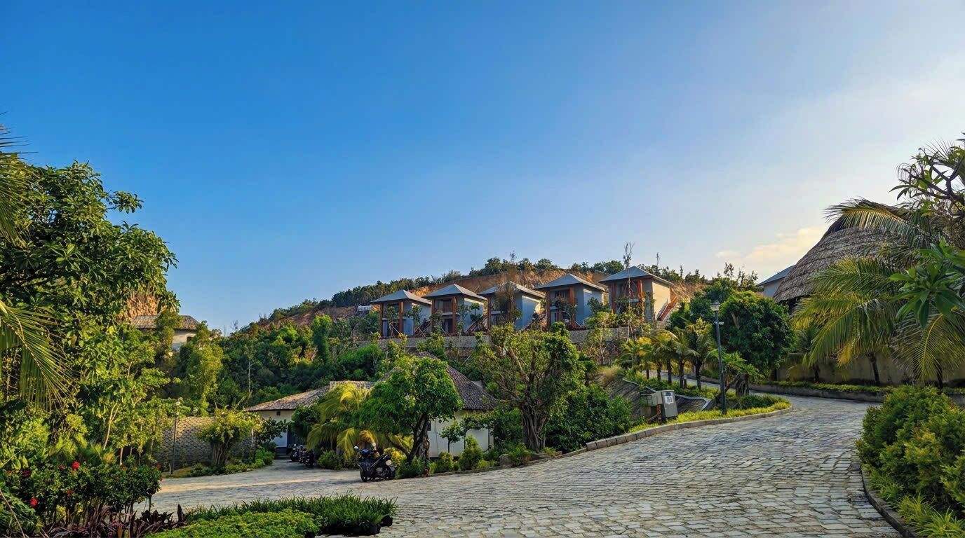 A resort with multiple villas, a cobblestone pathway, and lush greenery.
