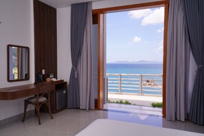Une pièce dotée d’un bureau, d’une chaise et offrant une vue sur la mer grâce à de grandes fenêtres.