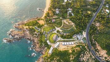 Vista aérea de una propiedad costera con un camino serpenteante, varios edificios y una playa.
