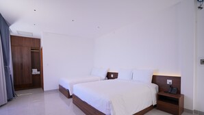 Ein modernes Schlafzimmer mit zwei Betten, einem Holzschrank und einem Nachttisch mit Telefon.