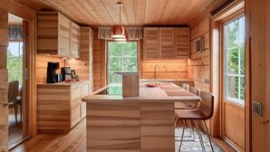 A wooden cabin interior with a kitchen island, wooden cabinets, and a dining area.