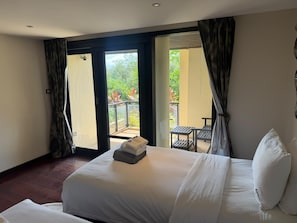 Une chambre d’hôtel avec un lit, une petite table et un balcon agrémenté de plantes.