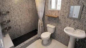 A bathroom with a patterned wall, a toilet, a sink, a shower curtain, and a window.