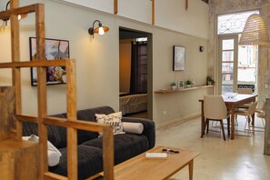 A modern living room with a sofa, a wooden coffee table, and a dining area with a table and chairs. - Casco Viejo Apartment (Panamá)