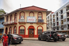 A building with a Coca-Cola sign, a balcony, and parked cars. - Casco Viejo Apartment (Panamá)