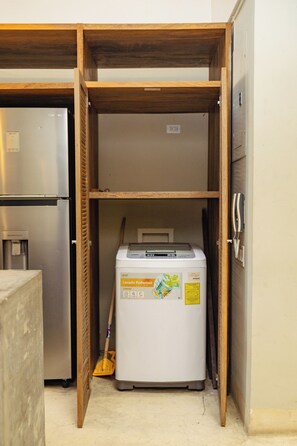 A compact kitchen with a built-in washing machine, a refrigerator, and a broom. - Casco Viejo Apartment (Panamá)