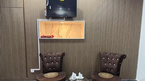 Una habitación con una televisión de pared, dos sillones tapizados y una mesita con adornos.