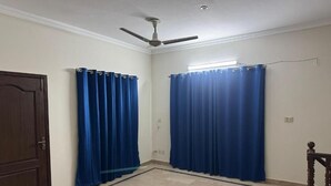 Una habitación con ventilador de techo, una puerta y dos juegos de cortinas azules.